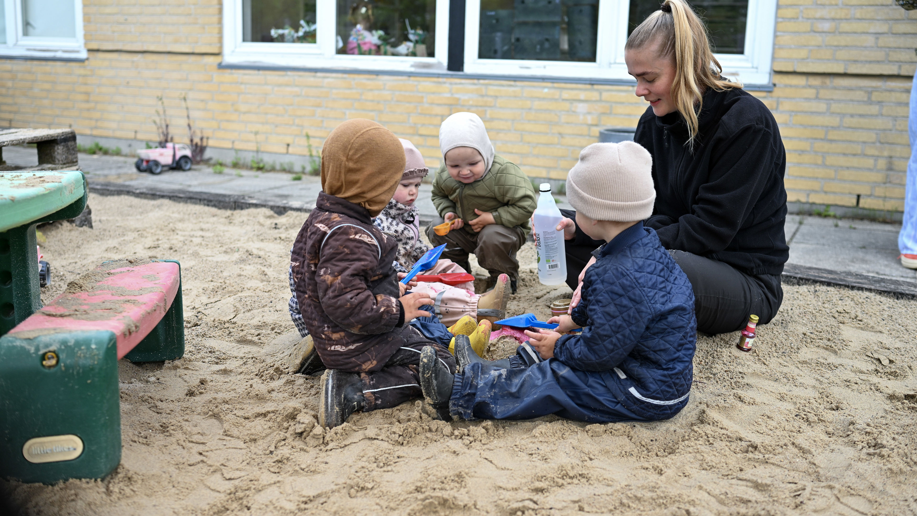 Voksen leger med børn i sandkasse