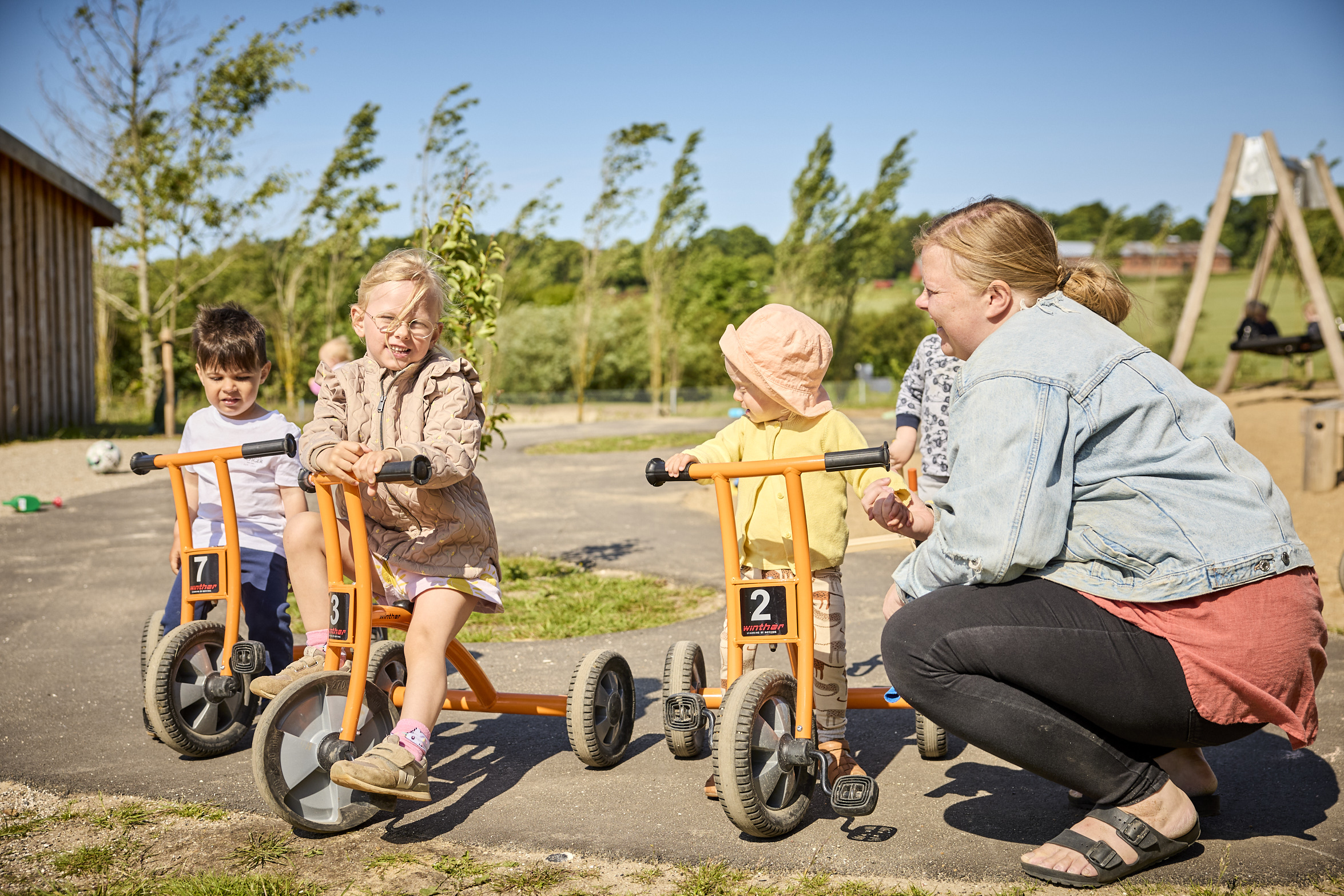 Voksen med børn på cykler i Børnehuset Dronningborg